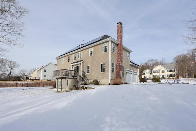 snow covered property with a wooden deck and solar panels