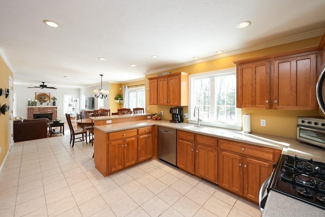 kitchen with sink, decorative light fixtures, a brick fireplace, kitchen peninsula, and stainless steel appliances