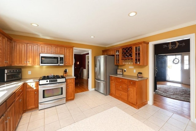 kitchen with stainless steel appliances, crown molding, and light tile patterned floors