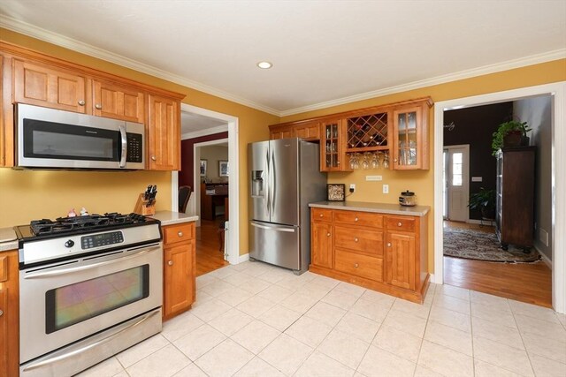 kitchen with light tile patterned floors, ornamental molding, and stainless steel appliances