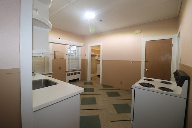 kitchen featuring white range with electric cooktop, radiator heating unit, sink, and white cabinets