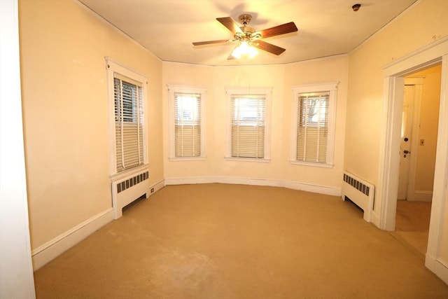 empty room featuring ceiling fan, radiator heating unit, and plenty of natural light