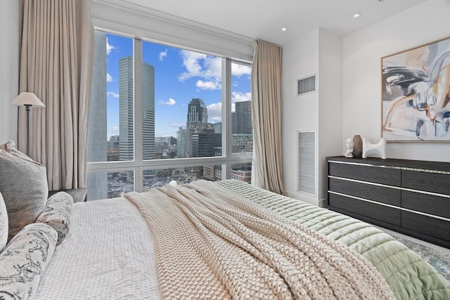 bedroom with recessed lighting, visible vents, and a city view