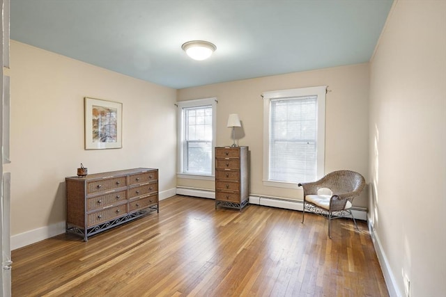 living area with hardwood / wood-style floors and a baseboard heating unit