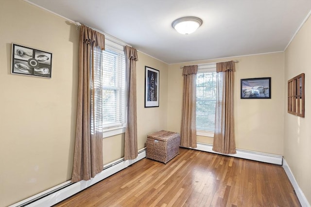 unfurnished room featuring a baseboard heating unit, a wealth of natural light, and light hardwood / wood-style floors