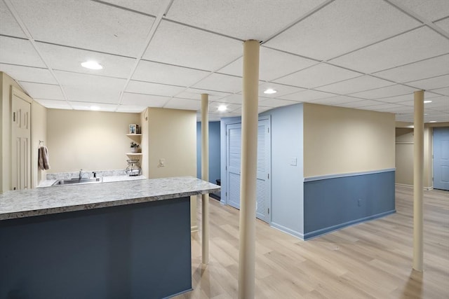 kitchen featuring a drop ceiling, sink, and light wood-type flooring