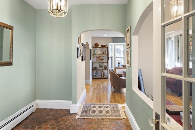 corridor featuring a baseboard heating unit and an inviting chandelier