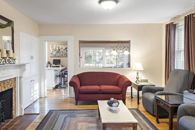 living room featuring wood-type flooring and a brick fireplace