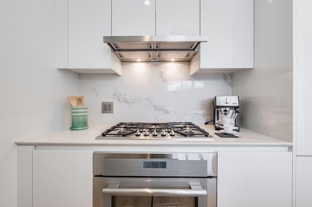 kitchen featuring backsplash, ventilation hood, white cabinetry, and stainless steel appliances