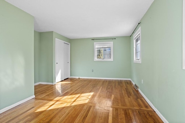 unfurnished room with hardwood / wood-style floors and baseboards