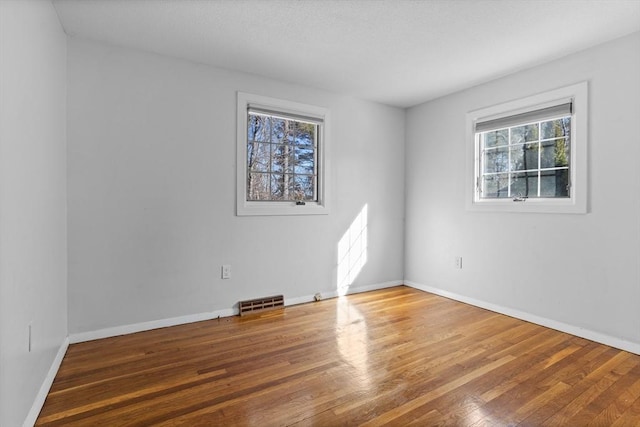 spare room with visible vents, baseboards, and wood finished floors