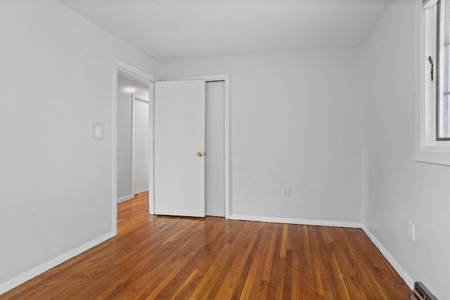 unfurnished bedroom with a closet, baseboards, and wood finished floors