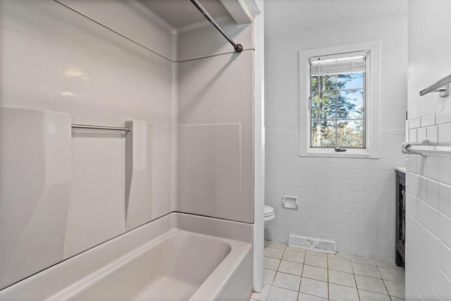 bathroom featuring tile patterned flooring, visible vents, toilet, shower / bathing tub combination, and tile walls