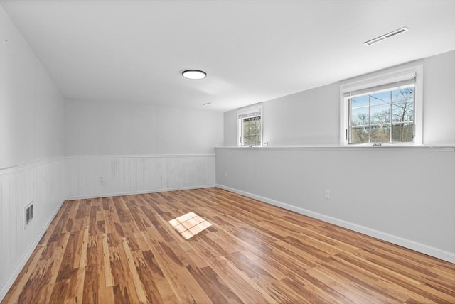 unfurnished room featuring visible vents, wood finished floors, and wainscoting