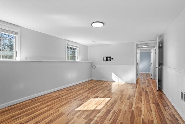 spare room with visible vents, baseboards, wood finished floors, and wainscoting