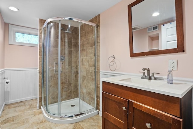 bathroom with visible vents, a shower stall, vanity, and a wainscoted wall