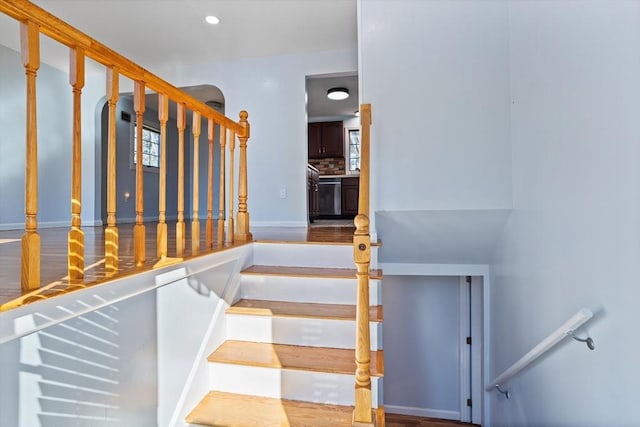 stairway with wood finished floors and recessed lighting