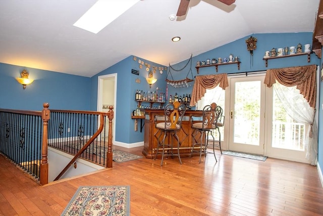 indoor dry bar featuring vaulted ceiling, wood finished floors, ceiling fan, and baseboards