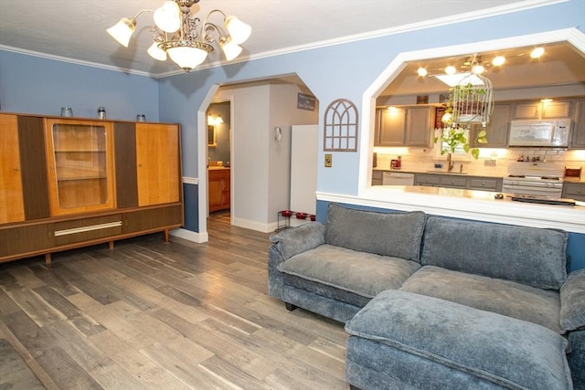 living room featuring a chandelier, wood finished floors, arched walkways, baseboards, and ornamental molding