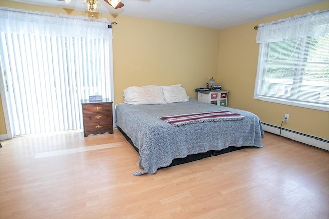 bedroom with wood finished floors and a baseboard heating unit