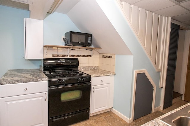 kitchen featuring black appliances, white cabinetry, tasteful backsplash, vaulted ceiling, and baseboards