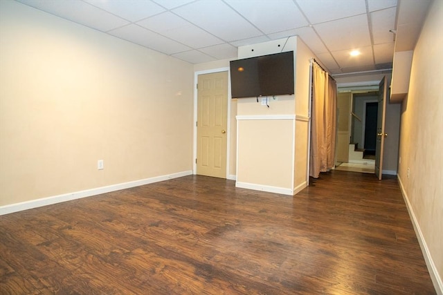 spare room with dark wood finished floors, a paneled ceiling, baseboards, and stairs