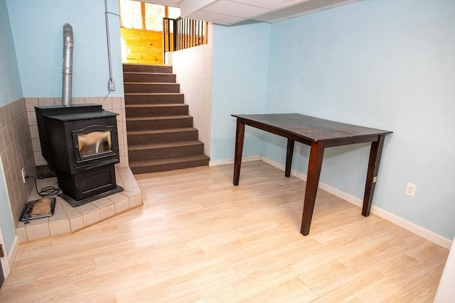 finished basement featuring wood finished floors, stairway, a wood stove, and baseboards