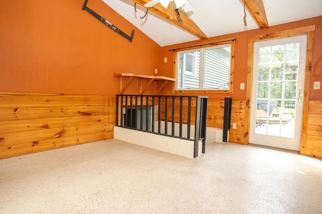 additional living space with speckle patterned floor, wood walls, and a ceiling fan