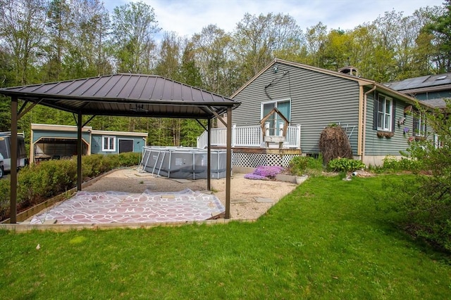view of green lawn featuring a gazebo, a patio area, a wooden deck, and an outdoor pool