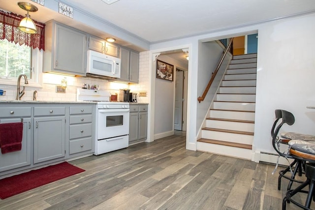 kitchen featuring white appliances, gray cabinetry, a sink, backsplash, and dark wood finished floors