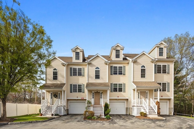 multi unit property with aphalt driveway, fence, and a garage