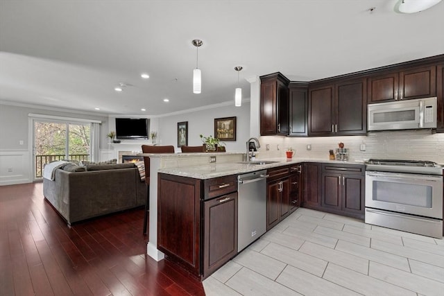 kitchen with crown molding, dark brown cabinets, open floor plan, a sink, and stainless steel appliances