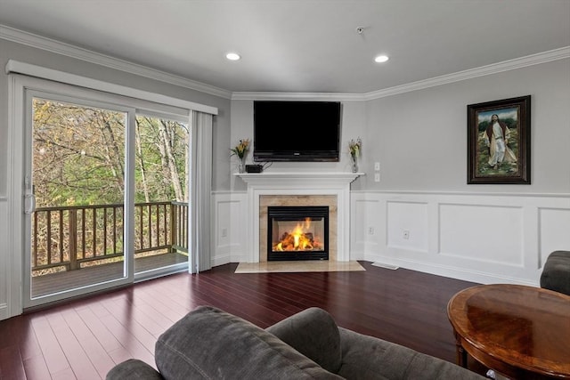 living room with crown molding, wainscoting, a decorative wall, wood finished floors, and a tile fireplace