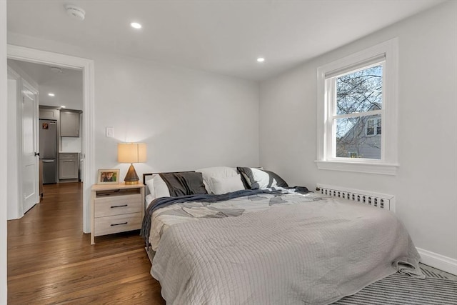 bedroom with freestanding refrigerator, recessed lighting, radiator heating unit, and dark wood-type flooring