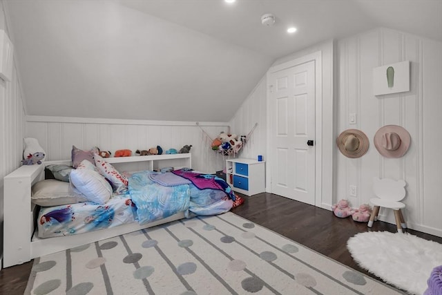 bedroom with dark wood-style flooring, vaulted ceiling, a wainscoted wall, and a decorative wall