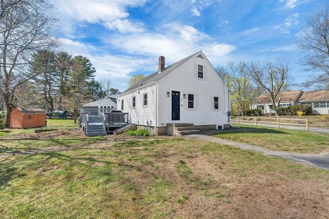 exterior space featuring a storage shed, an outbuilding, a chimney, and a front lawn