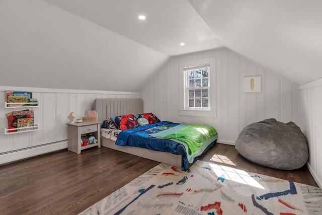 bedroom with a baseboard heating unit, a decorative wall, wood finished floors, and vaulted ceiling