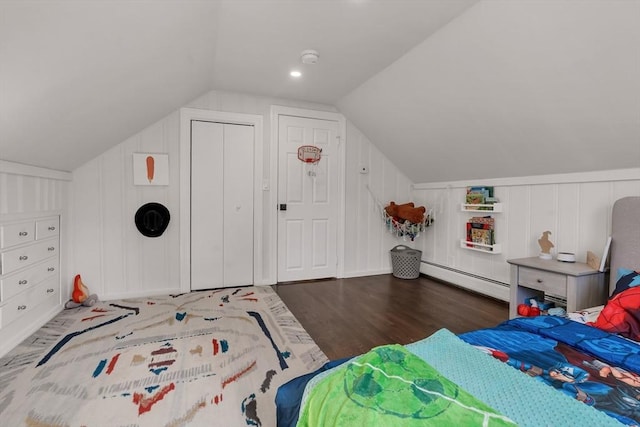bedroom featuring a baseboard heating unit, wood finished floors, vaulted ceiling, and a decorative wall