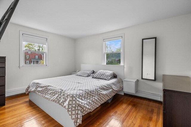 bedroom with a baseboard heating unit and hardwood / wood-style floors