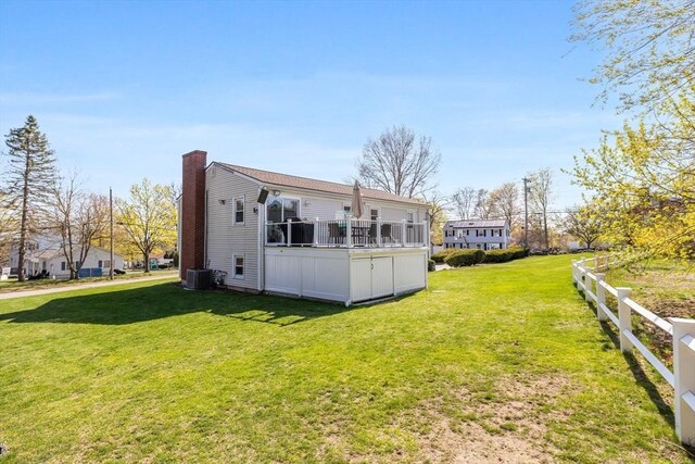 rear view of property with a lawn, central AC, a chimney, and fence