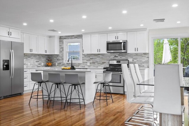 kitchen featuring white cabinets, stainless steel appliances, and a kitchen breakfast bar