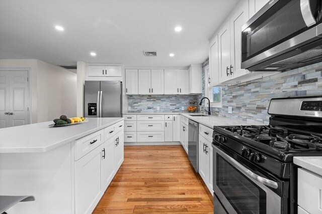 kitchen with visible vents, a sink, light countertops, stainless steel appliances, and white cabinetry