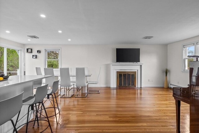 living area featuring visible vents, recessed lighting, light wood-style floors, and a baseboard heating unit