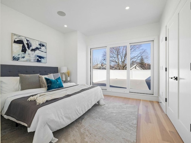 bedroom with access to exterior, wood finished floors, and recessed lighting