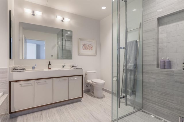 bathroom featuring vanity, a shower with shower door, and toilet