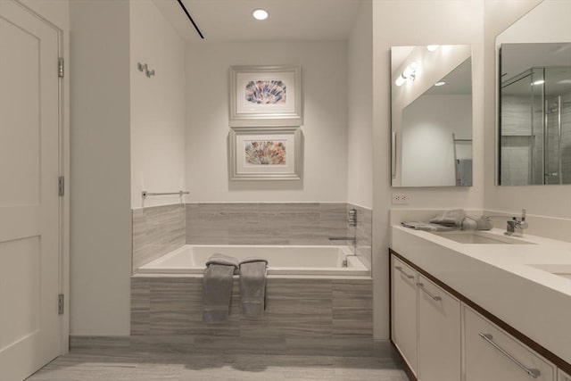 bathroom with tiled bath and vanity