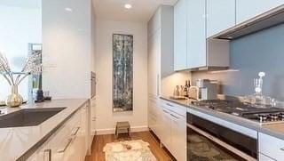 kitchen with dark hardwood / wood-style flooring, white cabinetry, wall oven, and stainless steel gas cooktop