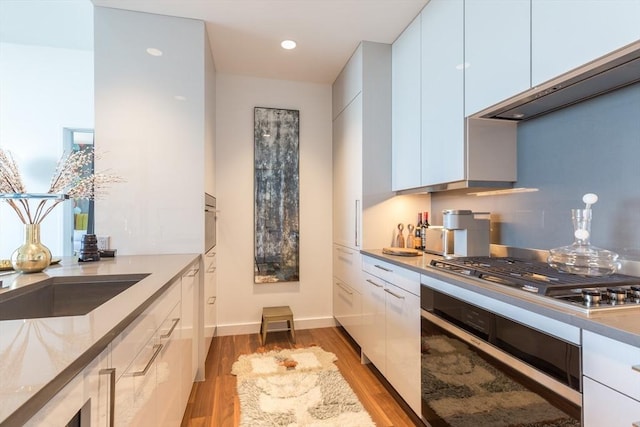 kitchen with white cabinets, appliances with stainless steel finishes, and light hardwood / wood-style flooring