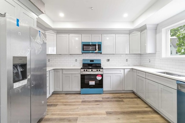 43 Pine St, Taunton, MA 02780 - kitchen with appliances with stainless steel finishes, light wood-style floors, tasteful backsplash, light countertops, and a tray ceiling