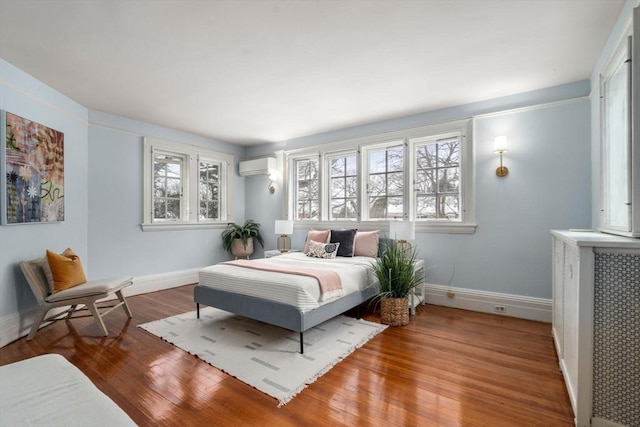 bedroom featuring hardwood / wood-style flooring and a wall mounted AC